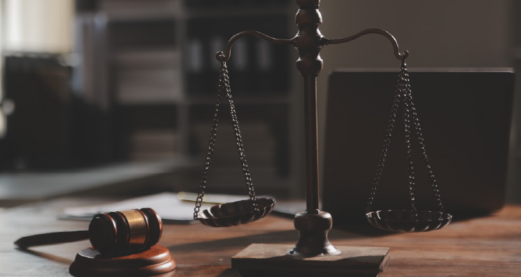 Imagem de martelo usado em tribunais ao lado da balança da justiça