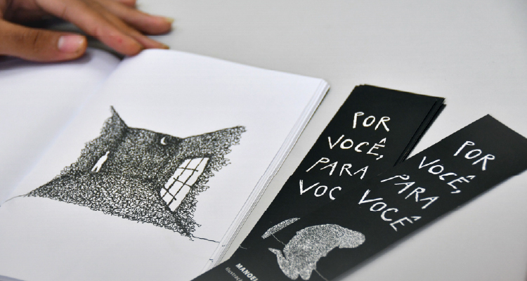 Fotografia de mão de jovem junto a livro aberto