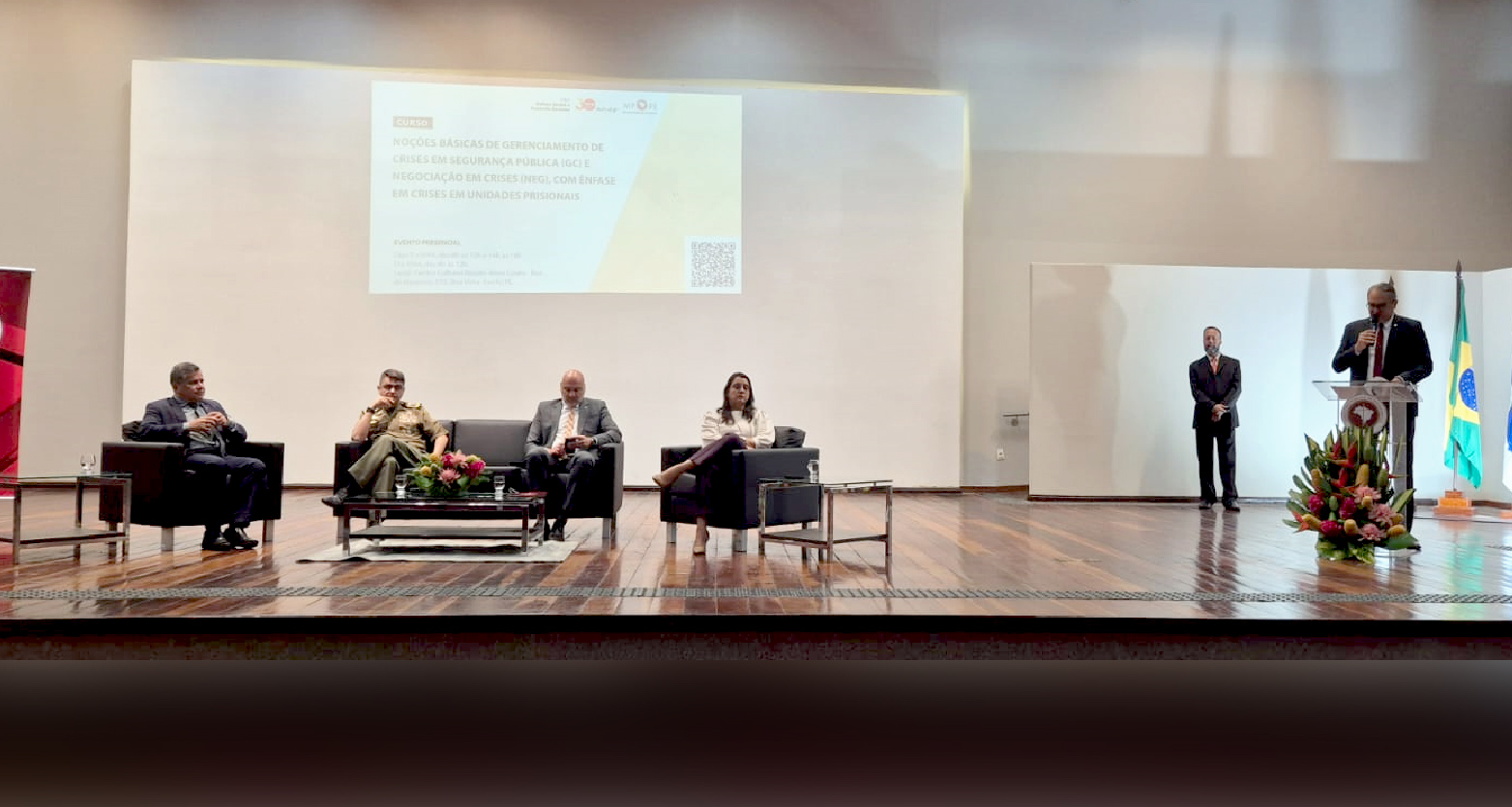 Fotografia do palco com palestrantes e PGJ discursando