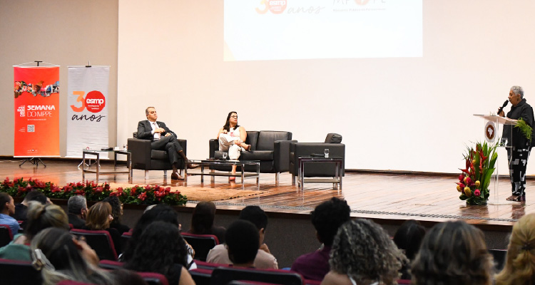 Fotografia do palco do Rossini com expositores sendo assistidos pela plateia